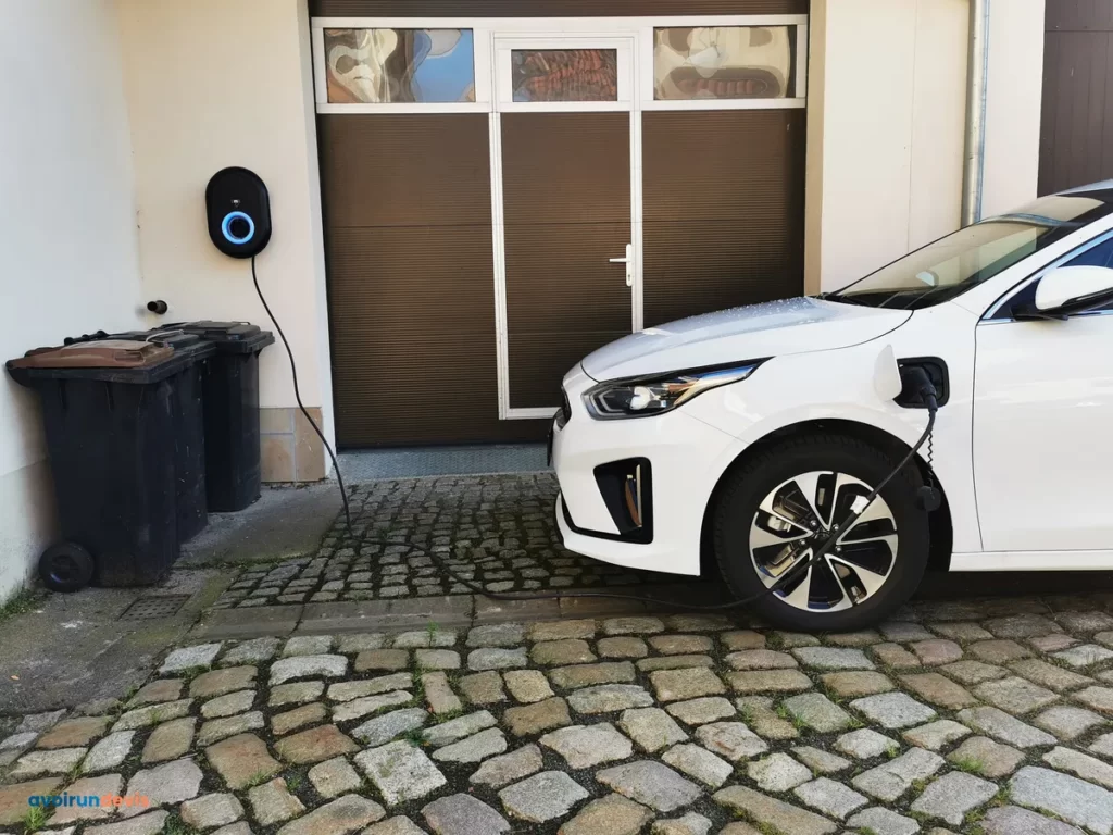 Une borne de recharge à coté d'un garage.