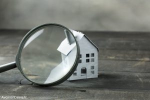 Une loupe posée à côté d'une maison miniature