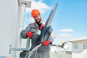 Un technicien posant une antenne satellite de TV