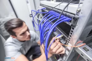 Un technicien câblant une baie informatique.