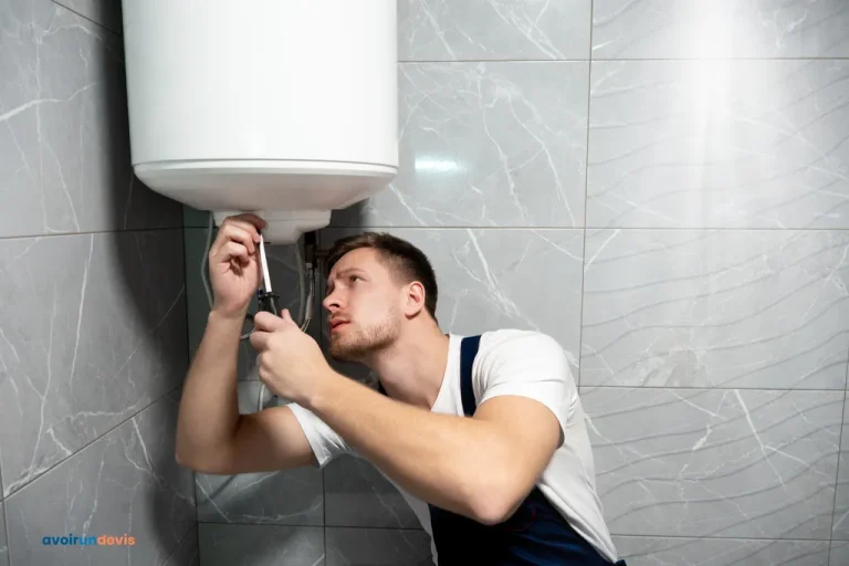 Jeune homme souriant en uniforme avec un tournevis à la main installant un chauffe-eau.