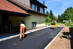 Des ouvriers travaillant sur une enrobée devant une maison.