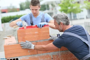 Deux maçons posant des briques pour monter un mur