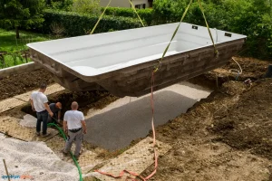 Une grue posant une piscine coque dans son trou