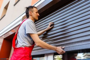 Artisan installant un volet roulant sur une fenêtre