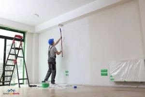 Un peintre travaille au rouleau dans un appartement.
