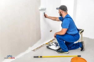 Un artisan peintre peint un mur au rouleau.